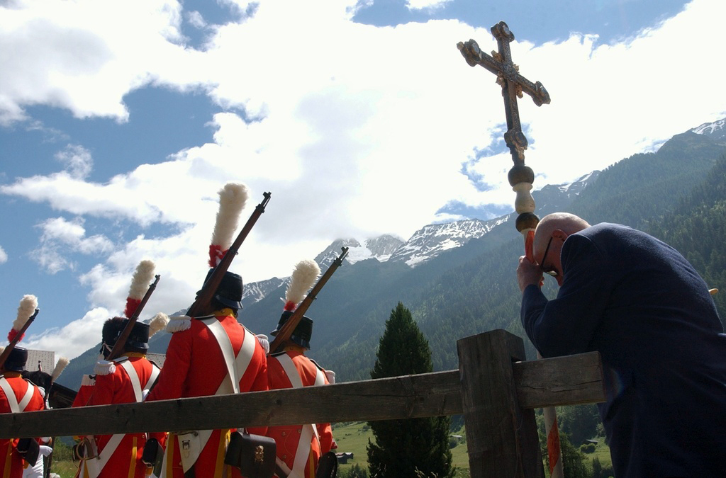 瓦莱州(Valais)的Kippel。在基督圣体圣血节游行中，一名男性正在祷告，旁边走过身穿古代服装的投弹手。(Keystone)