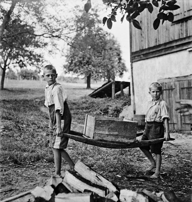 Immagine in biaco e nero di due bambini che trasportano un trogolo