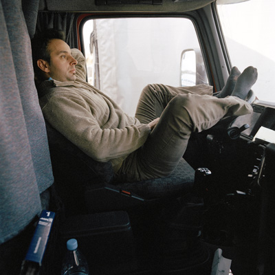 Lastwagenfahrer entspannt mit den Beinen auf dem Steuerrad.