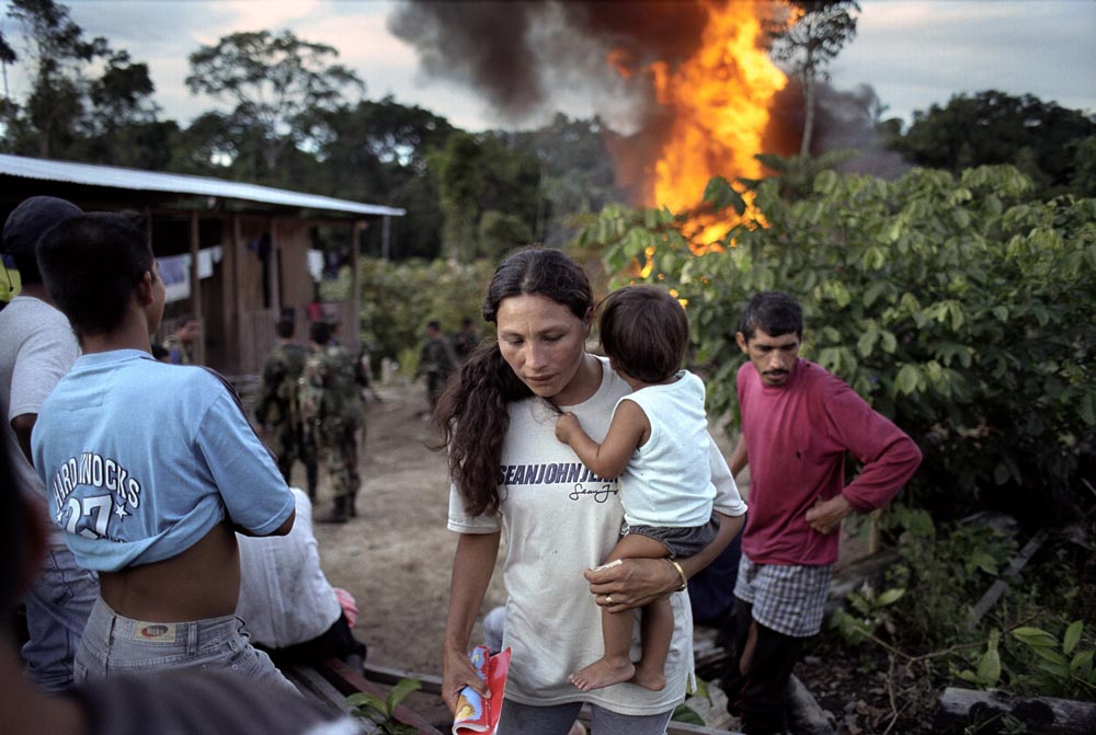 A mother and child flee a burning coca kitchen that might explode.