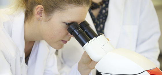 Photo of a woman looking into a microscope