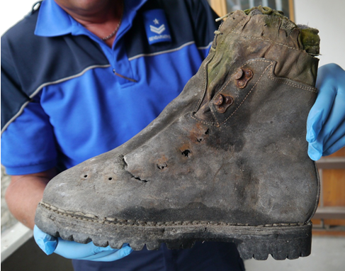 Ein Polizist zeigt einen Kletterstiefel