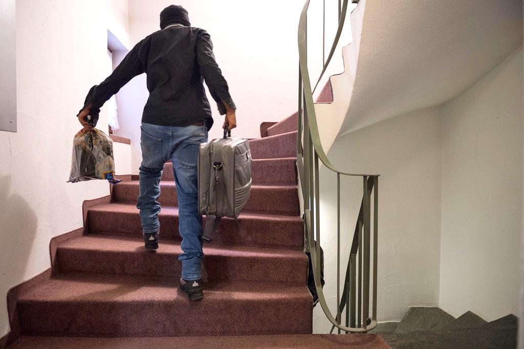لاجئ يحمل حقيبة ويصعد درجا