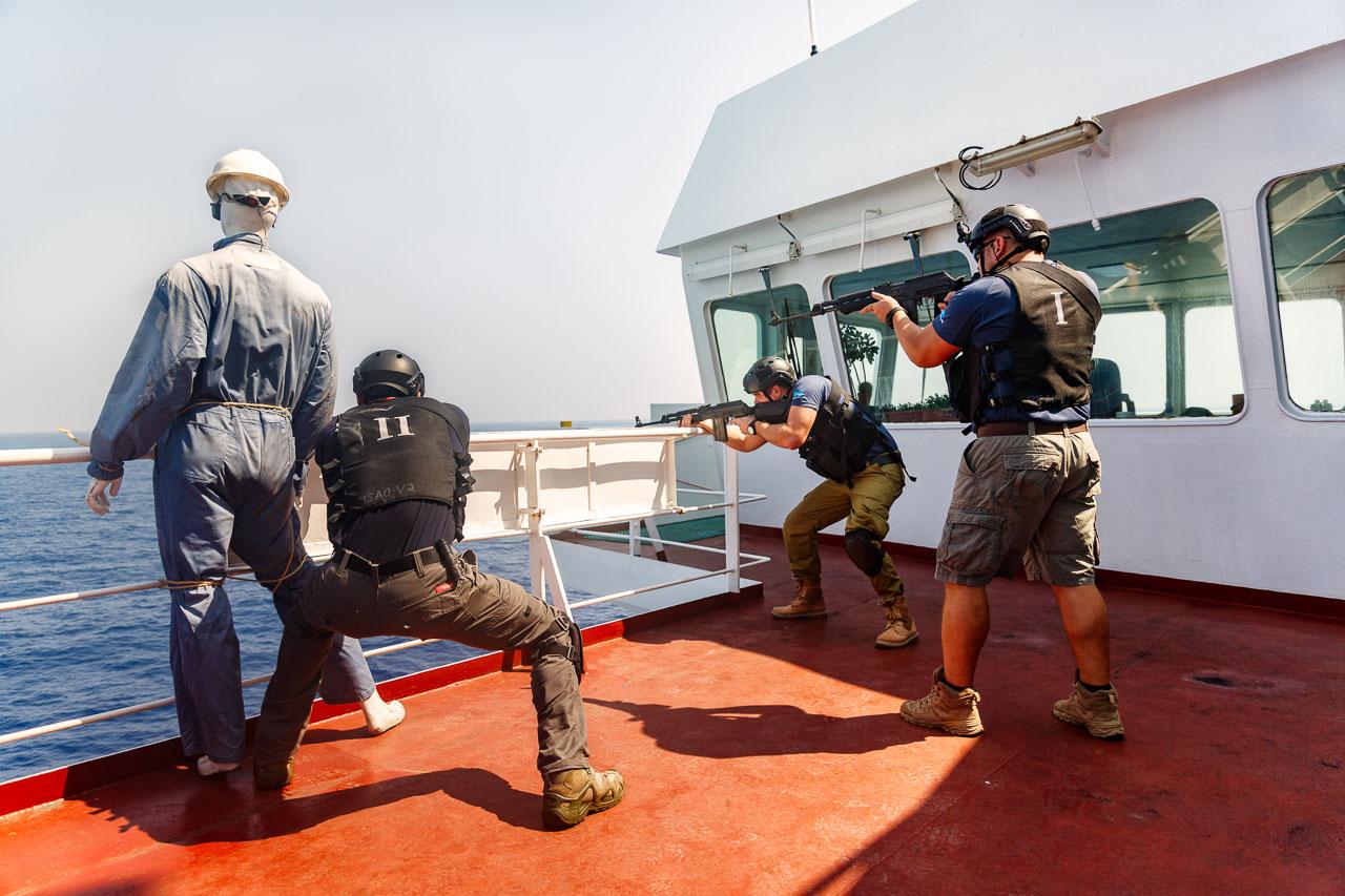 трое вооруженных мужчин на борту судна целятся в море