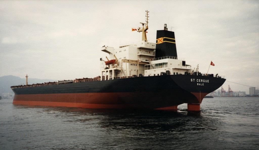 Immagine di una nave (battente bandiera svizzera e con la scritta St Cergue - Bale) nei pressi di un porto.