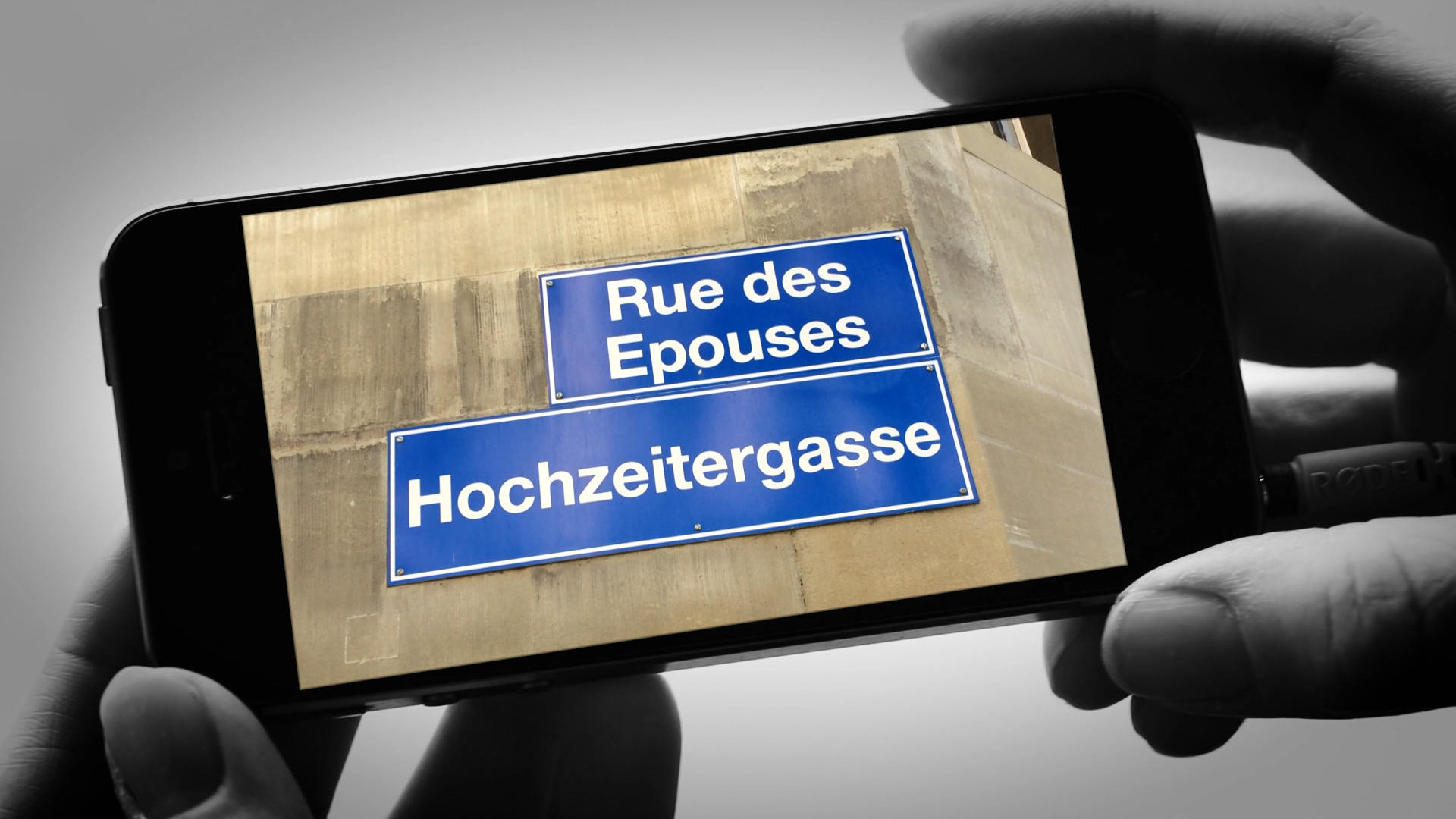 smartphone photographing of a road sign in French and in German in Switzerland