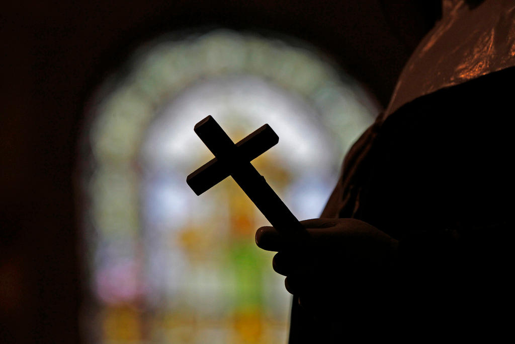 Una persona lleva una cruz en la iglesia