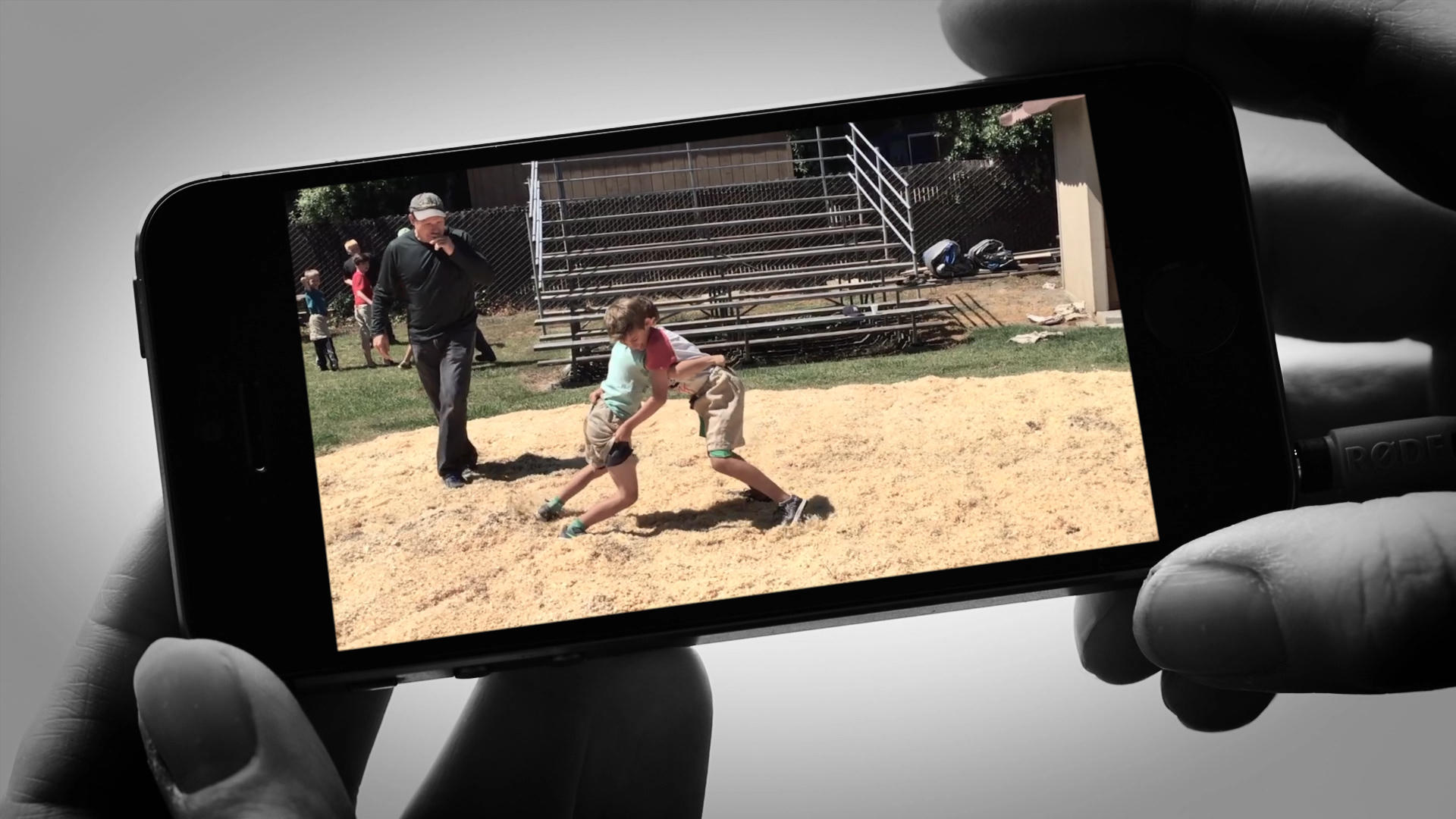 hands holding a smart phone with kids wrestling