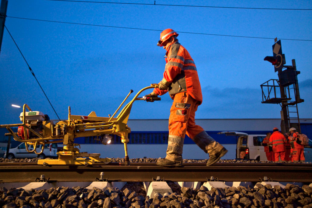 Ein Bahnarbeiter mit einer Maschine auf einem Gleis.