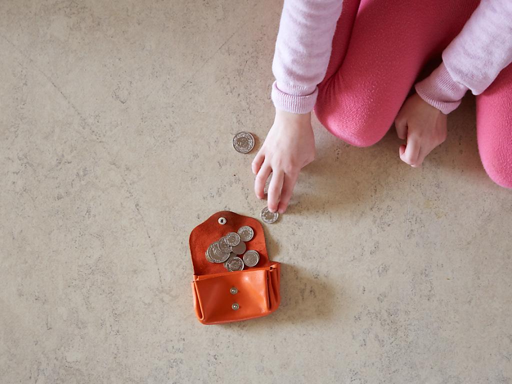 Kleines Mädchen mit Geldmünzen