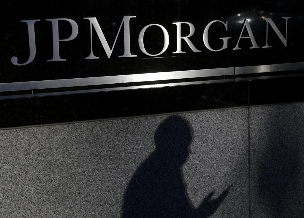 Logo de JP Morgan en la fachada de un inmueble en penumbras con la sombra de una persona.