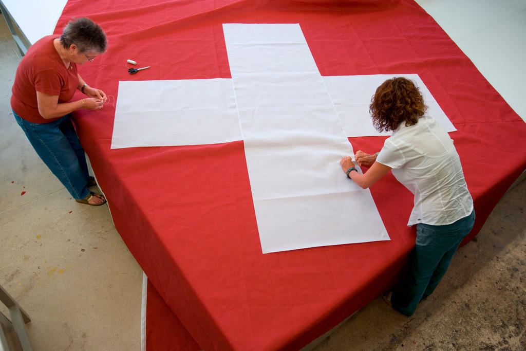 two women sewing a swiss national flag