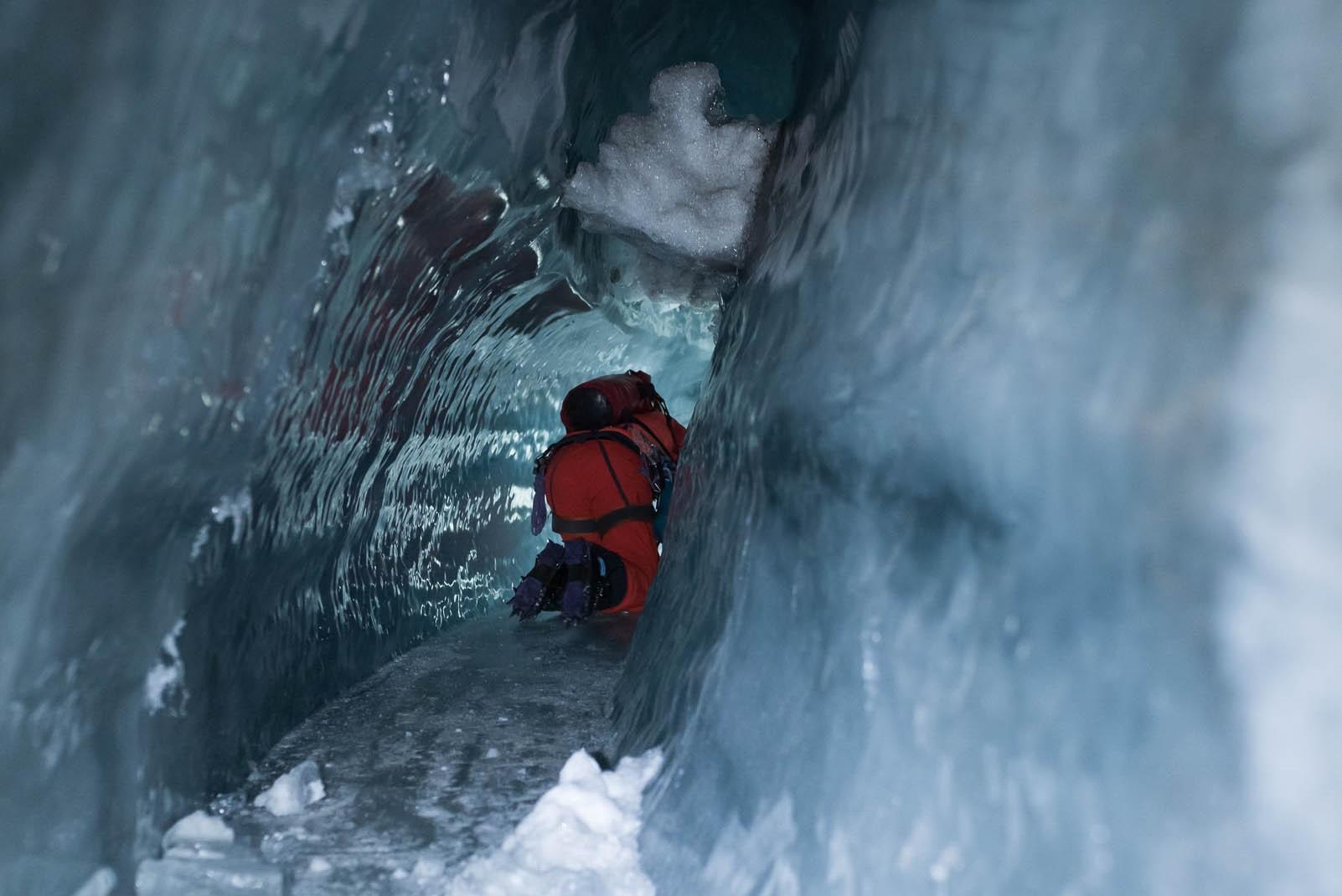Man crawls through narrow icy tunnel on all fours