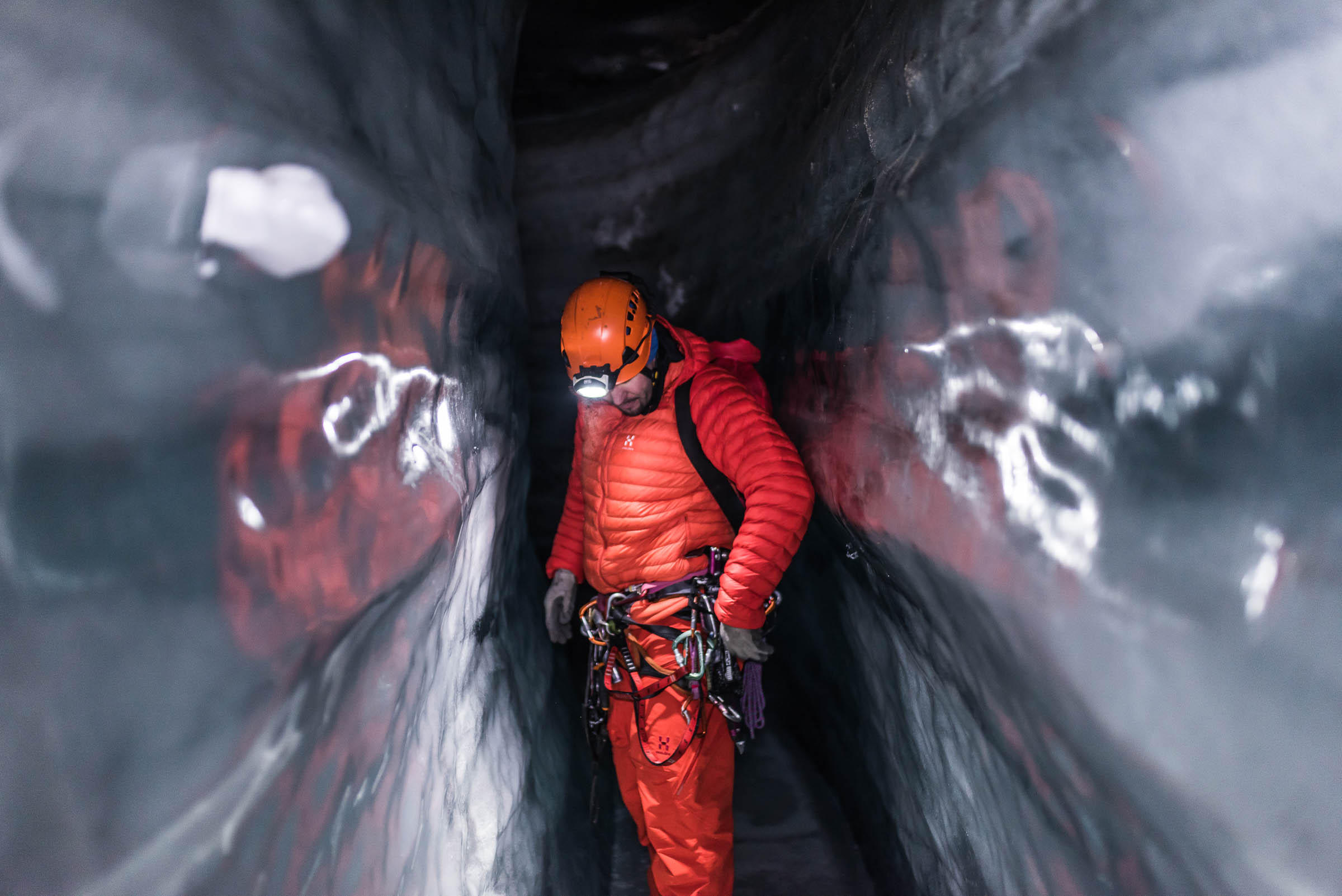 Man in narrow icy space, peers down