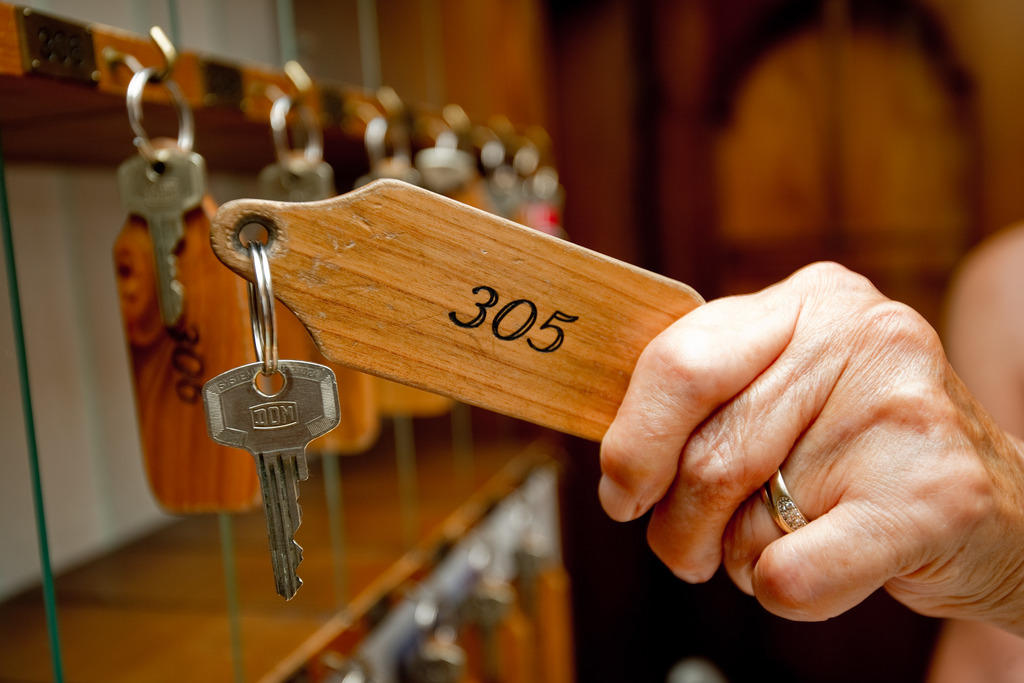 A hotelier selects a wooden hotel room key from its hook.