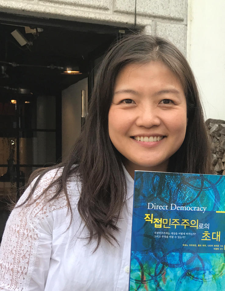 Yoon Lee holding a book on Direct Democracy
