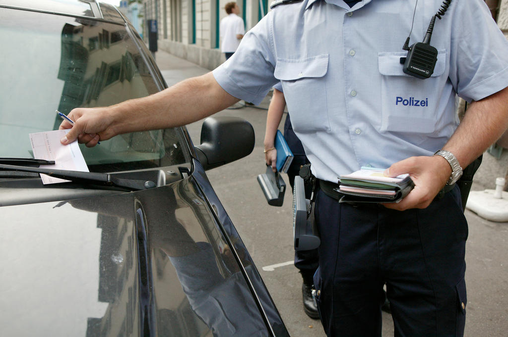 A policeman puts a parking ticket on a car windscreen