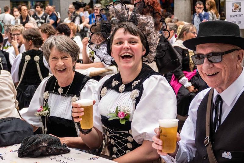 Pessoas com trajes tradicionais seguram copos de cerveja