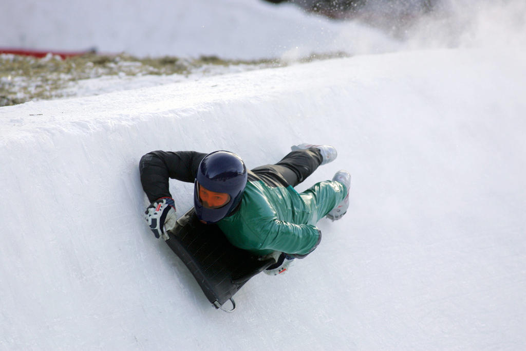 A man in helmet and protective suit hurtles down the Cresta Run on a skeleton sledge
