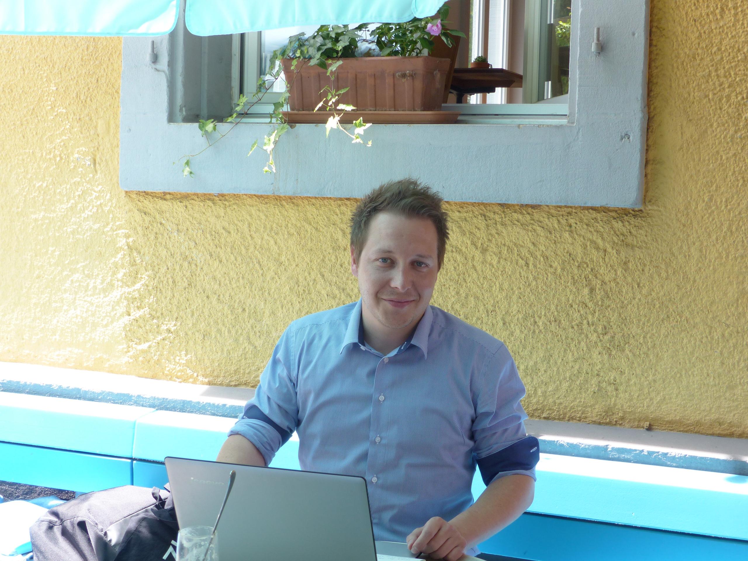 Lukas Wegmüller, co-leader of the New European Movement Switzerland sitting outside with his laptop on the table