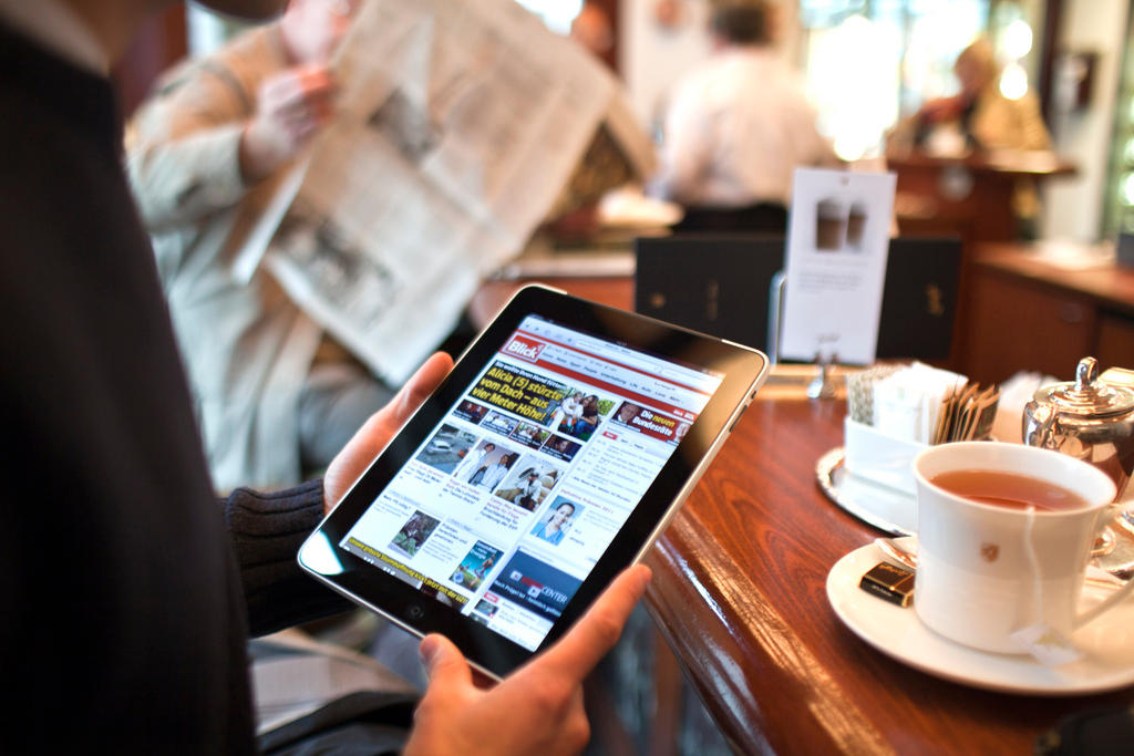 man reads tablet of blick newspaper