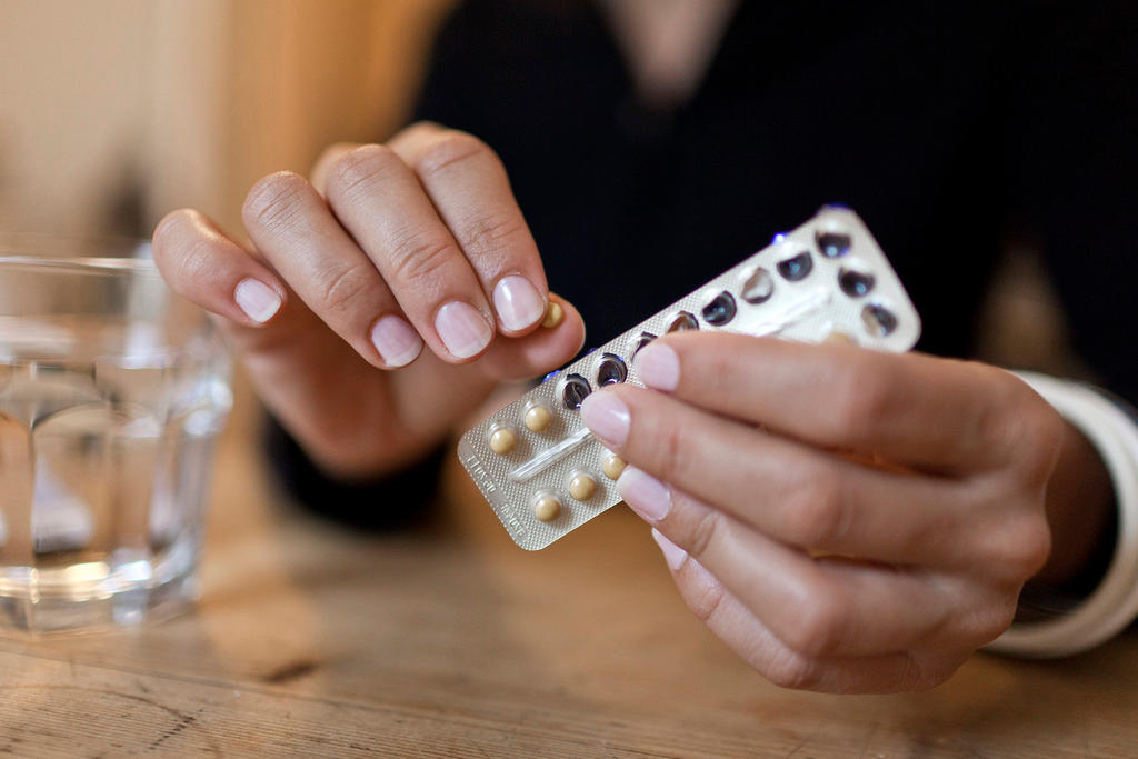 A woman opens a packet of contraceptive pills