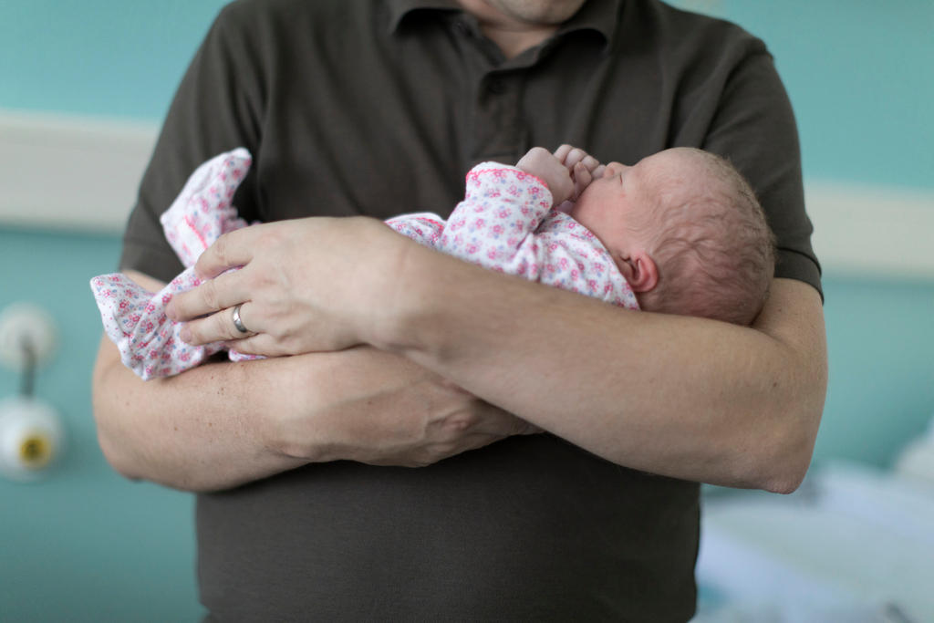 Neonato in braccio al padre.