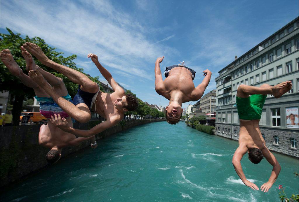 Vier junge Männer springen in Thun in die Aare.