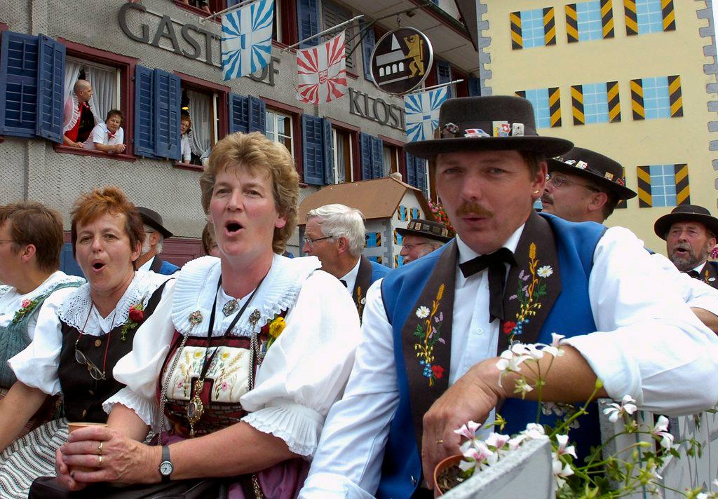 Men and women yodelers sing a village procession at a Swiss yodeling festival.