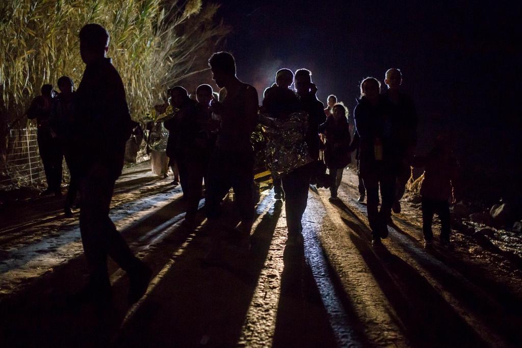 لاجئون ومهاجرون يمشون فوق طريق إثر وصولهم من شاطئ تركي إلى جزيرة ليبسوس اليونانية في عام 2015