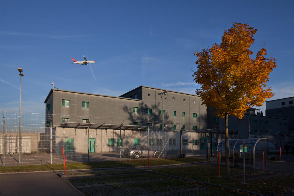 An plane takes off above the roofs of the prison at the airport of Zurich