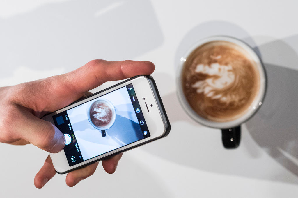 A person takes a smartphone photo of his coffee