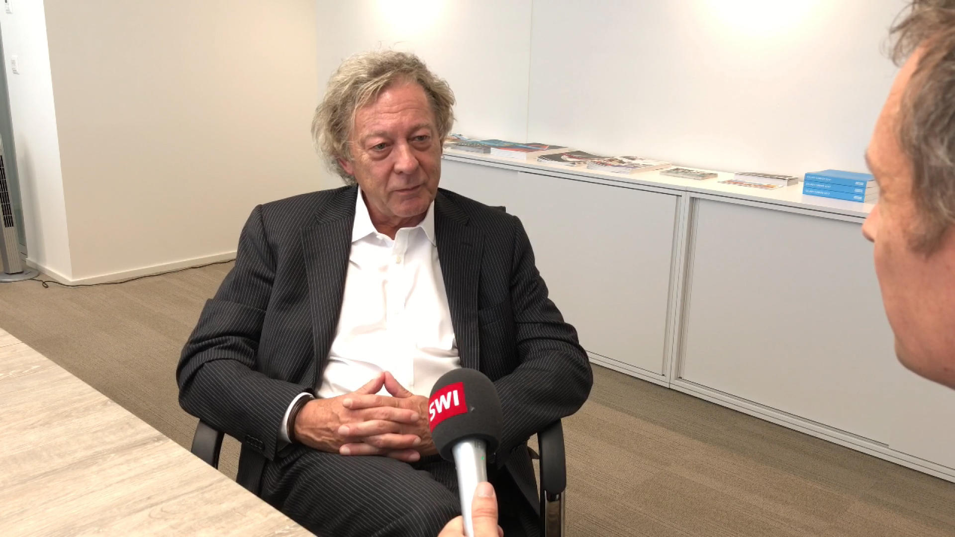 Robert Walters sitting in a dark suit in an office during an interview