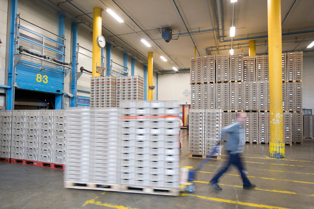 A Migros worker pulling a huge stack of crates