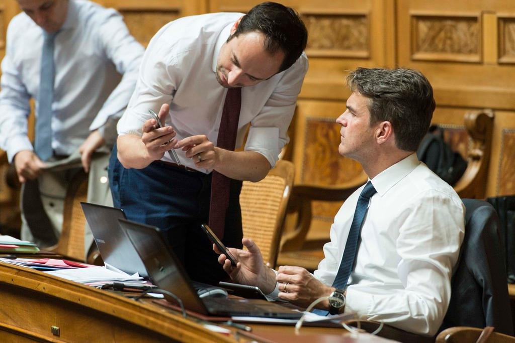 Politicians in parliament with smartphones in hand