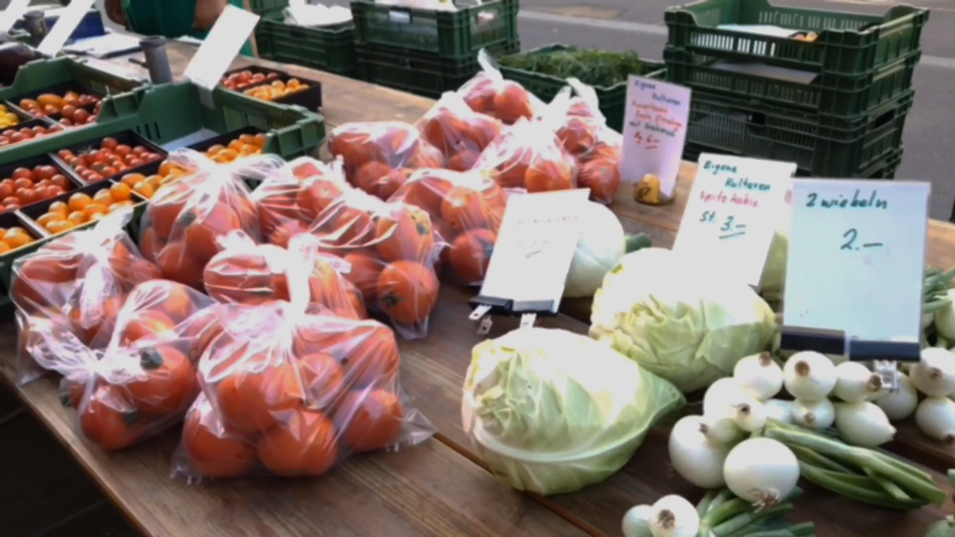 Un estand de mercado con tomates, cebolletas, coles...