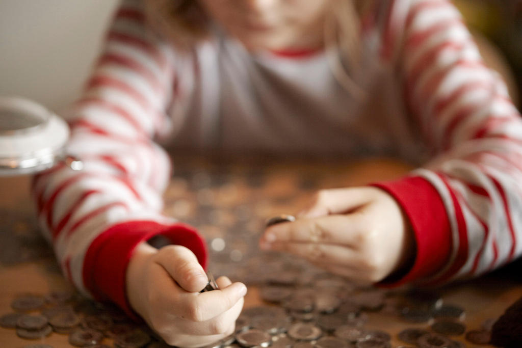 In un immagine puramente illustrativa, una bambina conta il denaro contenuto nel suo salvadanaio.