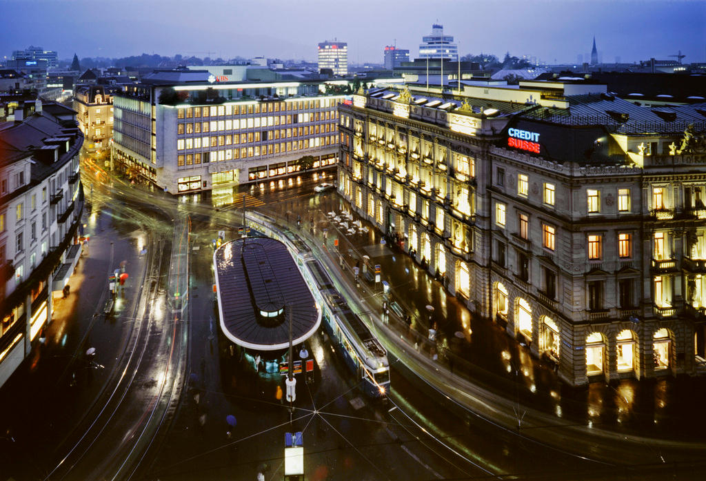 Zurich Paradeplatz by night with lit buildings and trams in a busy street