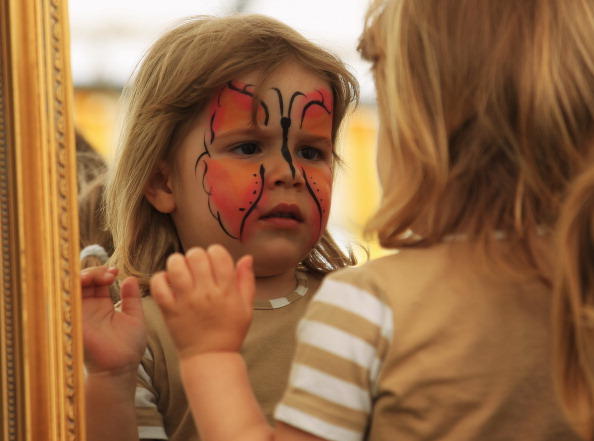 A little girl looks in a mirror