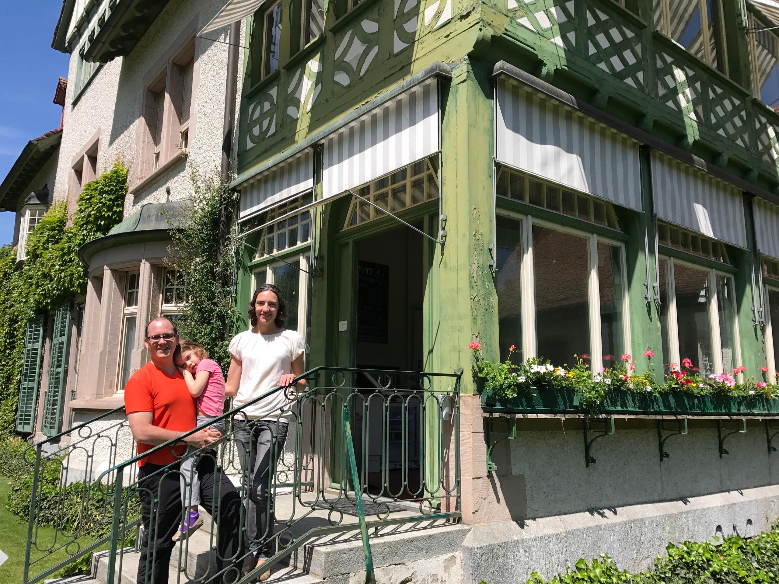 Man, woman and little girl in front of a villa