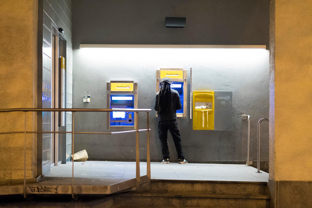 Customer waiting in front of cash dispenser of Post Finance