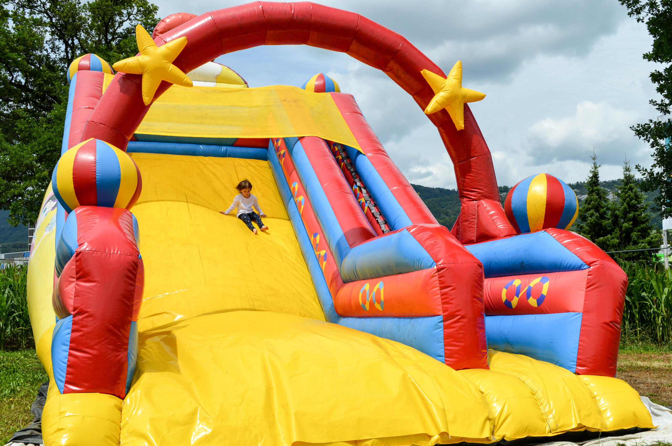 Ein Kind rutscht in einer Hüpfburg die Rutschbahn runter.