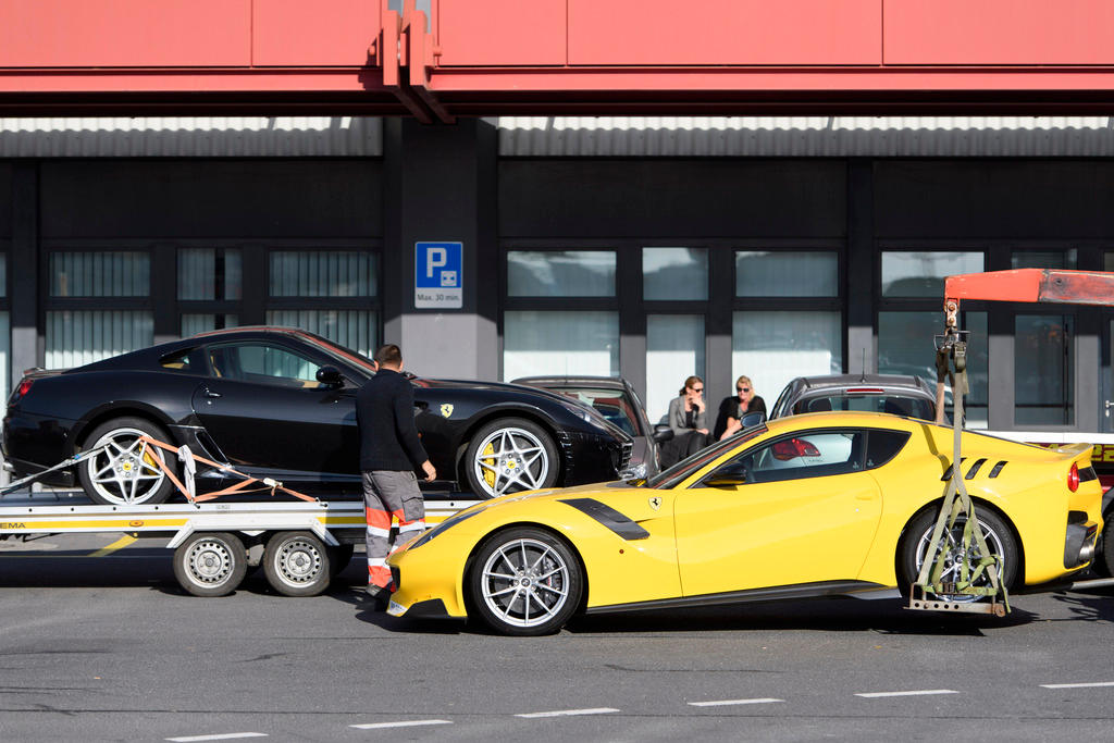 Two sports cars, one black and one yellow, are strapped to trailers.