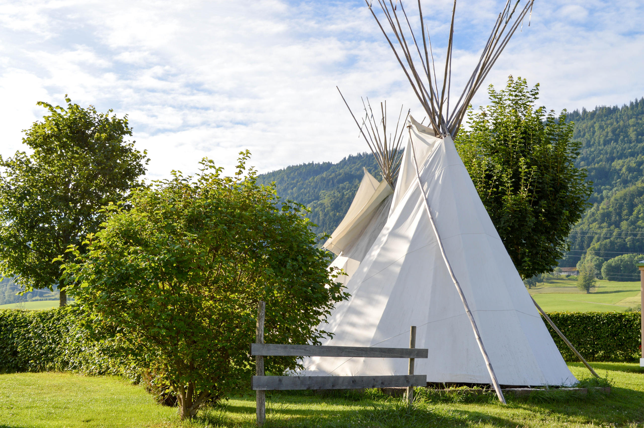 Zwei Tipis stehen im Grünen eines Campingplatzes