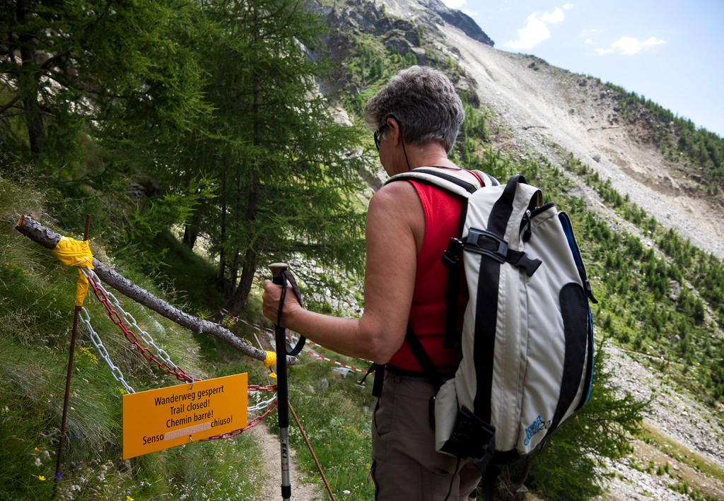 「通行止め」の札の前で立ち止まる登山客