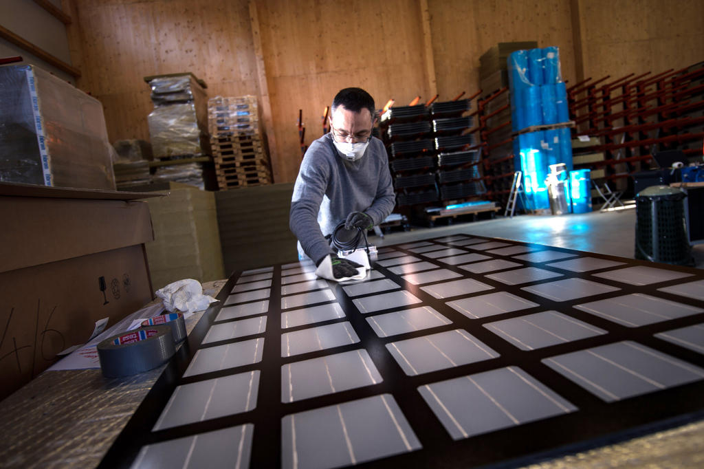 Un operaio pulische dei pannelli fotovoltaici all interno di un capannone