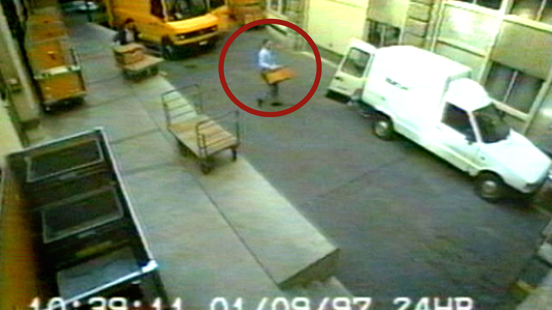 La cámara graba a uno de los atracadores que lleva una caja a una furgoneta blanca.