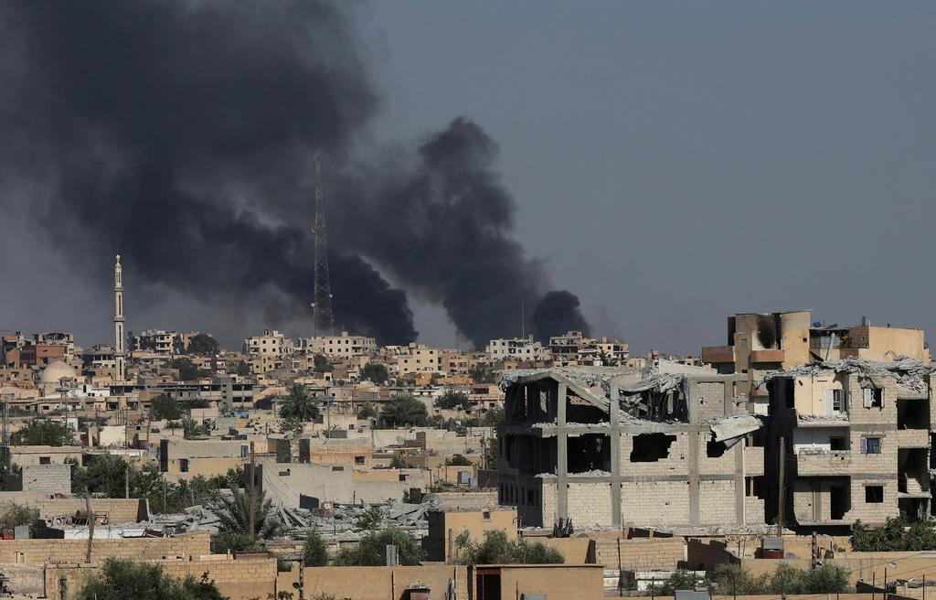 vista di Raqqa semidistrutta con colonne di fumo causate da bombardamenti