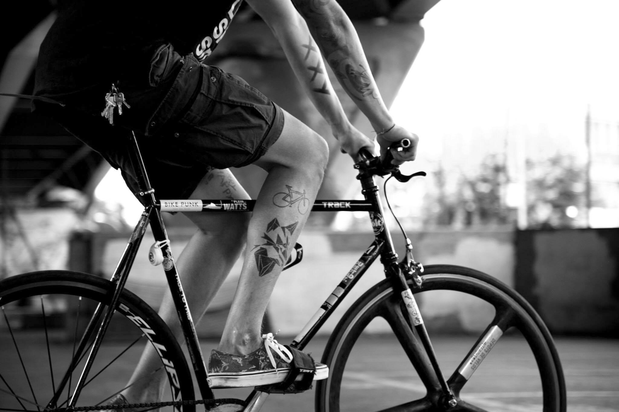 Ein Mann mit tätowierten nackten Beinen und Armen fährt Velo