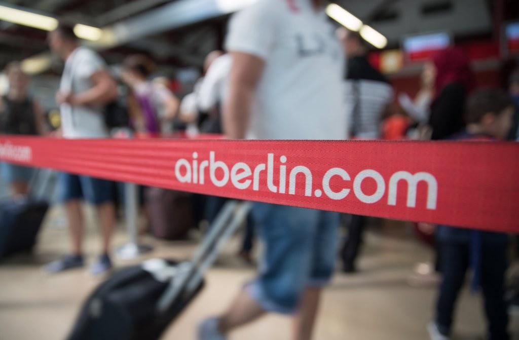 A red tape with the wordds airberlin.com with passengers at an airport